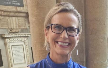 Emma Walmsley smiling in front of Oxford University building.