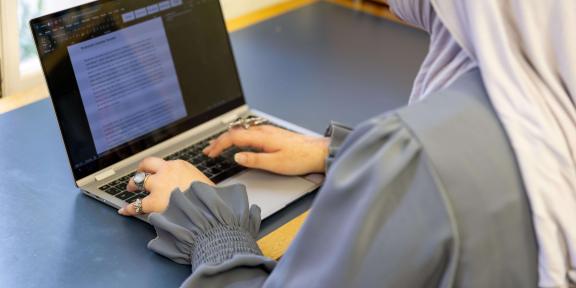 A student typing on their laptop
