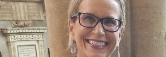 Emma Walmsley smiling in front of Oxford University building.